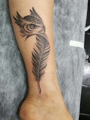 Tatouage plume avec une partie haute qui représente unhibou